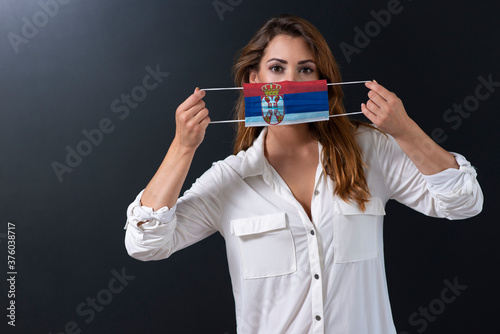 Coronavirus COVID-19 in Serbia.Woman in medical protective mask with the image of the flag of Serbia