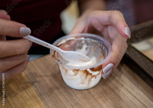 Woman's hand with spoon and ice cream cup