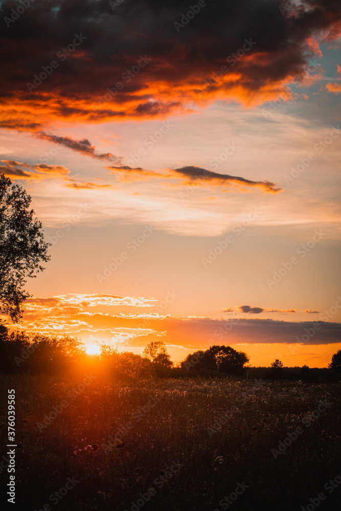 Colorful and dramatic sunset view with illuminated clouds and burning sky and nature countryside view