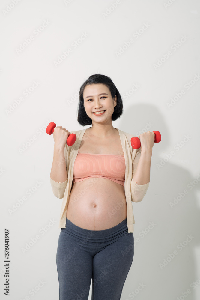 Closeup of pregnant woman doing exercises with dumbbells in the room Closeup of pregnant woman doing exercises with dumbbells in the room