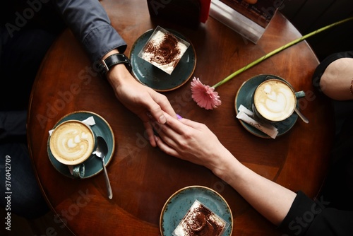 A man holds a woman's hand on a table where coffee stands