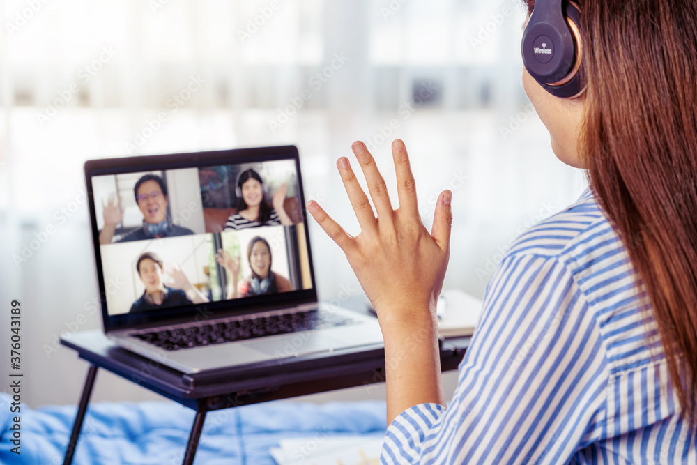 Rear View of Asian Business woman say hello with teamwork colleague in video conference when Coronavirus outbreak, Covid-19 pandemic, online meeting, Social distancing and new normal concept