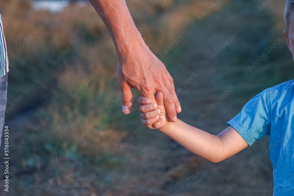 A Hands of a happy child and parent in nature in a park by the road A Hands of a happy child and parent in nature in a park by the road