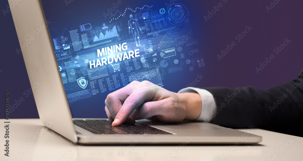 Businessman working on laptop with MINING HARDWARE inscription, cyber technology concept Businessman working on laptop with MINING HARDWARE inscription, cyber technology concept