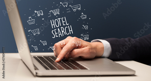 Businessman working on laptop with HOTEL SEARCH inscription, online shopping concept