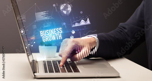 Businessman working on laptop with BUSINESS GROWTH inscription, new business concept