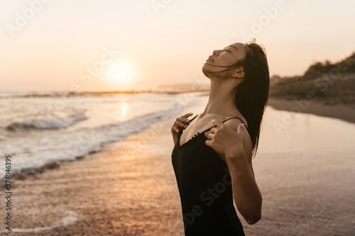 Smile Freedom and happiness chinese woman on beach. She is enjoying serene ocean nature during travel holidays vacation outdoors. asian beauty. summer time #376046395