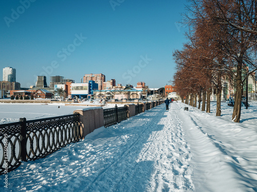 People walking on the embankment in Chelyabinsk in winter time. Alley with a trees near the river in Chelyabinsk © Ayrat A.