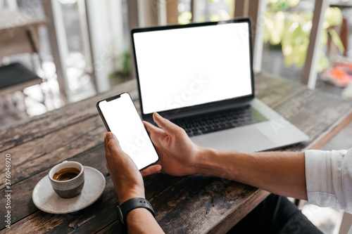 Cropped view of man with laptop computer th copy space for your text or promotional content, mobile phone, having coffee, sitting at a cafe