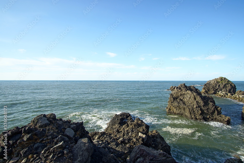 Rocks on the coast, rocks receive sunshine on blue sky, sea, ocean, Japan