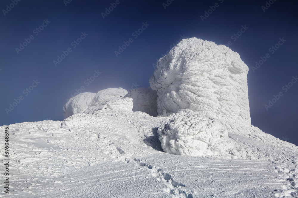 The old observatory covered with textured snow. Winter scenery. Beautiful landscape of high mountains and blue sky. Lawn covered with white snow. Wallpaper snowy background. Free space for text.