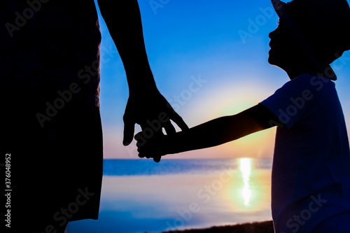 A Hands of happy father and child by the sea on nature silhouette travel