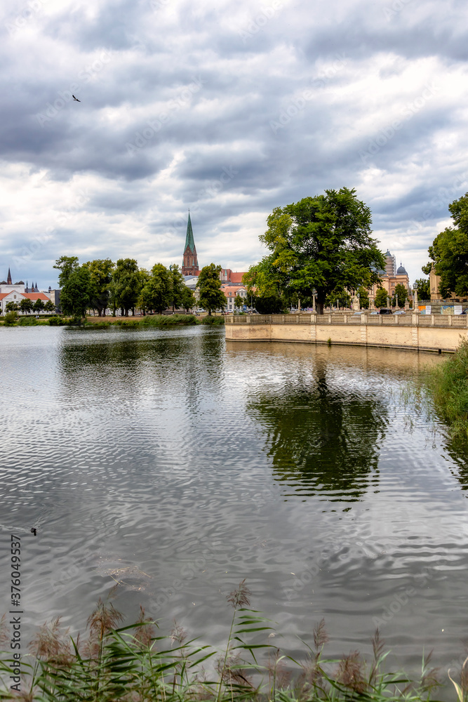Fototapeta premium Widok na Burgsee z ogrodu zamkowego przy zamku Schwerin w kierunku Kolumny Zwycięstwa, centrum miasta i katedry w Schwerinie w sierpniu 2020 r.
