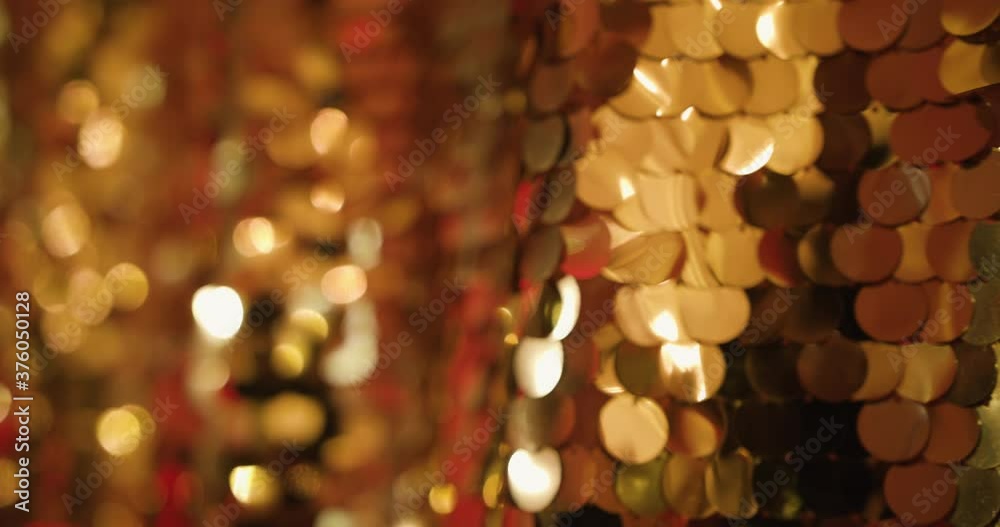 Festive gold fabric texture with shiny particles close up. Beautiful shiny golden background of sequins and bokeh