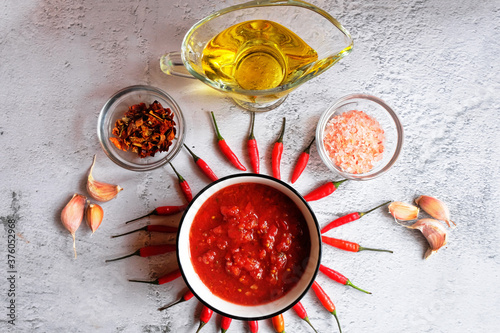 Small bowl of homemade harissa with red chili. Adjika, hot harissa sauce - spicy hot paste of chilli pepper on white background.