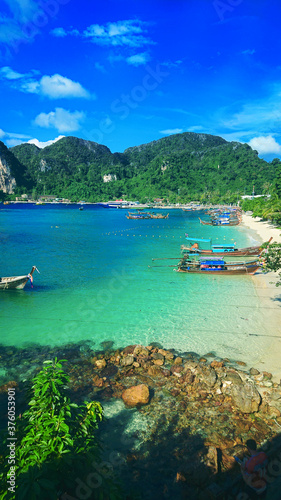 Beautiful view on the sea and Phi Phi Don island near Phuket in Thailand. In the distance you can see gorgeus azure water, golden sand, mountains, jungle and thai boats.