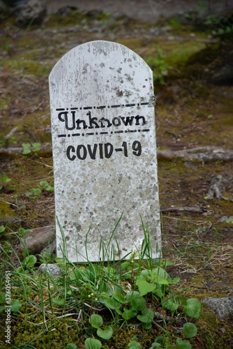 Old dirty tombstone with Unknown written on the top and COVID-19 written under it