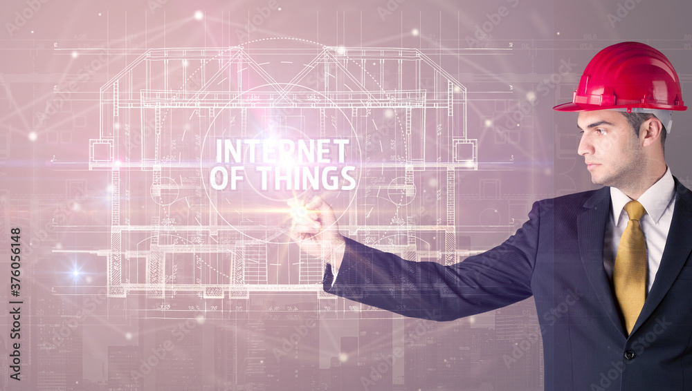 Handsome architect with helmet drawing INTERNET OF THINGS inscription, new technology concept Handsome architect with helmet drawing INTERNET OF THINGS inscription, new technology concept