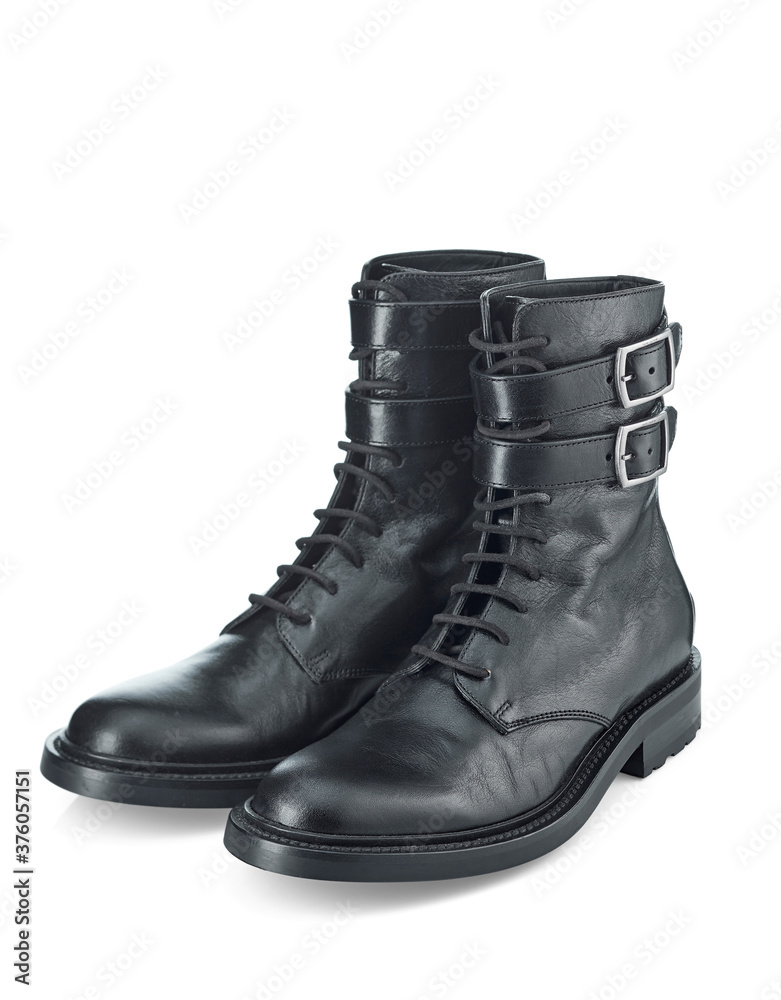 Black biker boots made of durable leather with a small heel, isolated on a white background with a shadow. The view from the top at an angle.