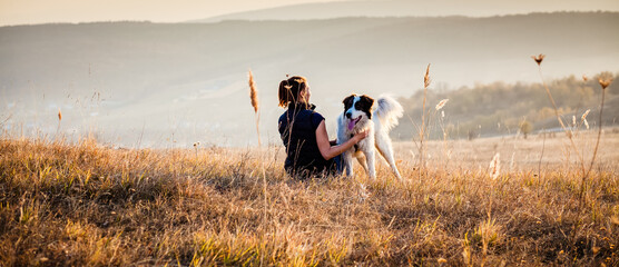 woman with dog relaxing in autumn landscape