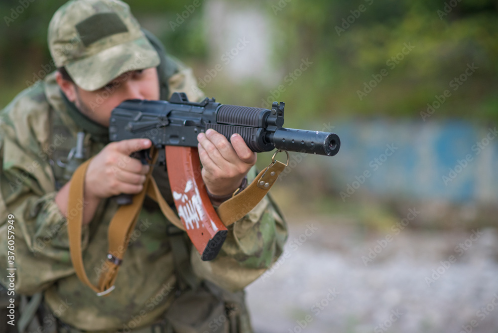 A professional airsoft player aims at his opponents A professional airsoft player aims at his opponents