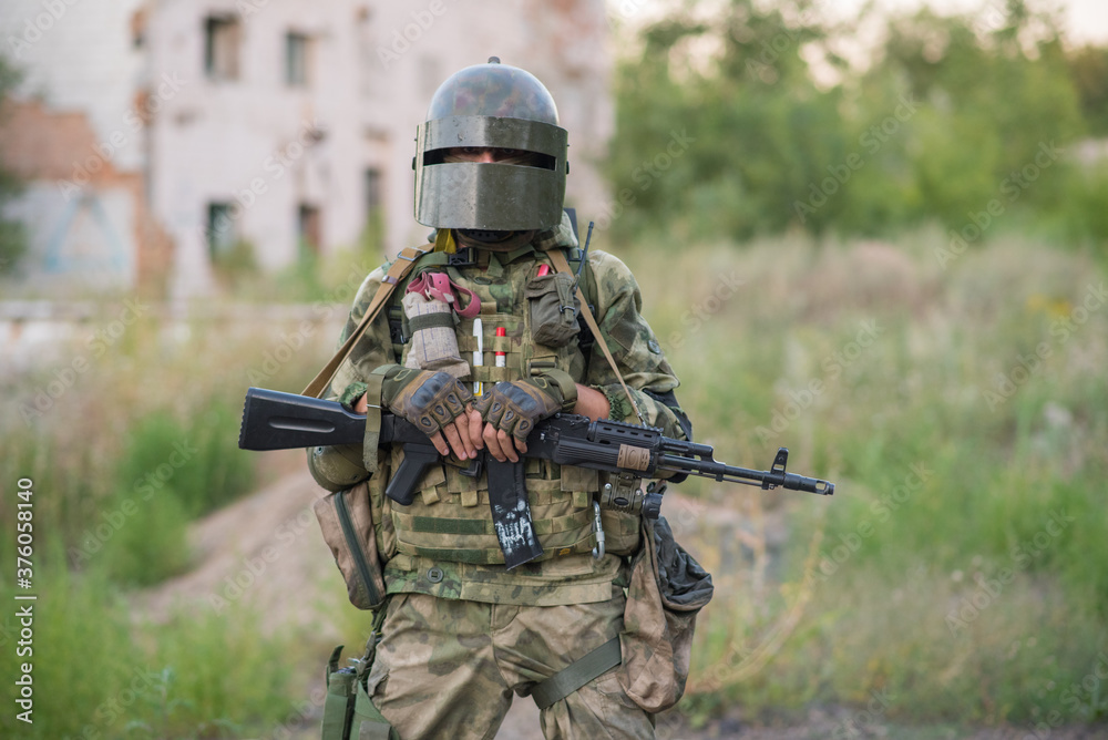 Fototapeta premium Professional airsoft player stands in a big helmet and a machine gun