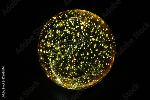 Transparent glass ball with dark background and yellow lighting effects.