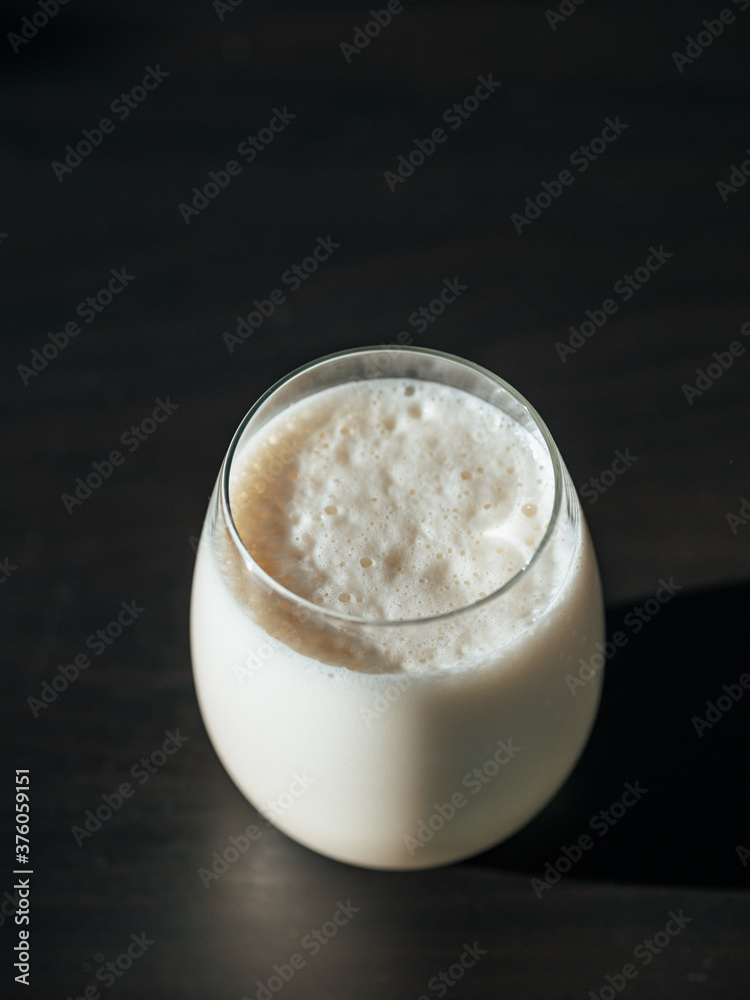 Protein milkshake in tumbler glass over black background. Vertical. Copy space for text or design. Protein milkshake in tumbler glass over black background. Vertical. Copy space for text or design.