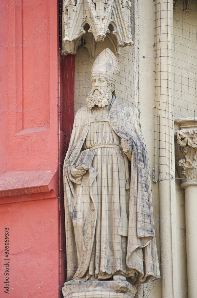 Fototapeta premium Ancient wall sculpture of a monk at the main facade of Mary chapel in historical downtown of Wurzburg, Germany