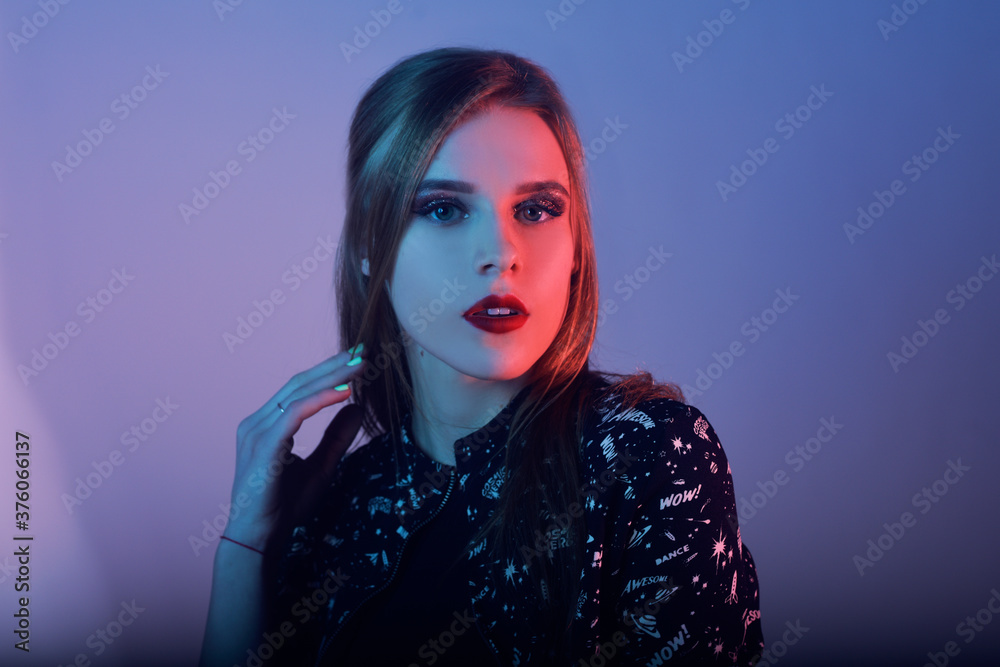 Model with air style. Woman in colorful bright lights posing in studio, portrait of beautiful girl with trendy make-up and manicure. Art design, colorful make up. Over colourful blue background. Model with air style. Woman in colorful bright lights posing in studio, portrait of beautiful girl with trendy make-up and manicure. Art design, colorful make up. Over colourful blue background.