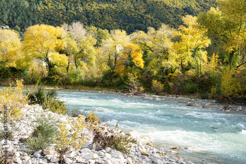 A river in Provence flows between stones and pebbles. Trees with autumnal colors. Bunches of shrubs grow in the rocky outcrops. A river in Provence flows between stones and pebbles. Trees with autumnal colors. Bunches of shrubs grow in the rocky outcrops.