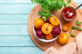 Yellow and red plums in a plate and jar of plum jam on blue wooden table flat lay, autumn fruit preserves concept, copy space