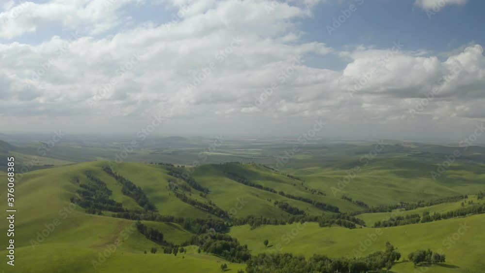 Scenic aerial panoramic view of idyllic rolling hills spring landscape in with lush green mountain pastures in evening light at sunset