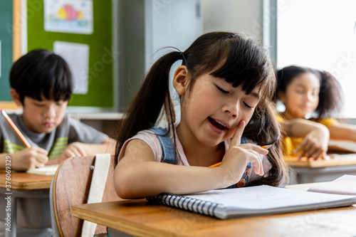 Portrait of an Asian child girl student thinking and solving the subject matter studied in the classroom. School education concept