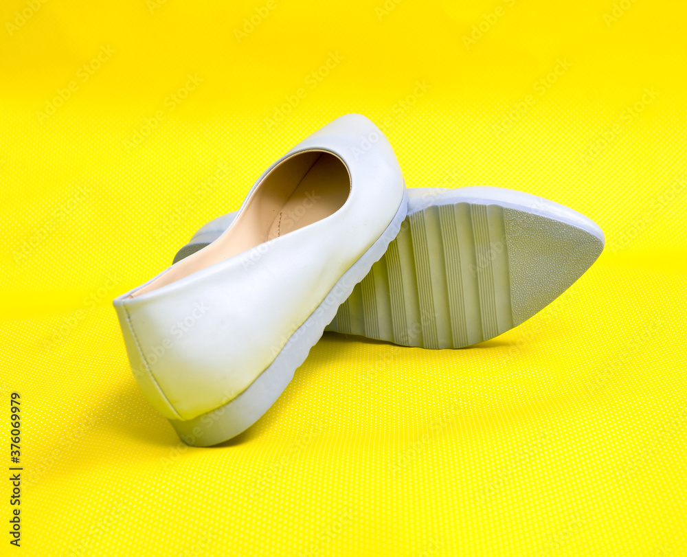 Pair of milk blue female summer shoe on yellow background