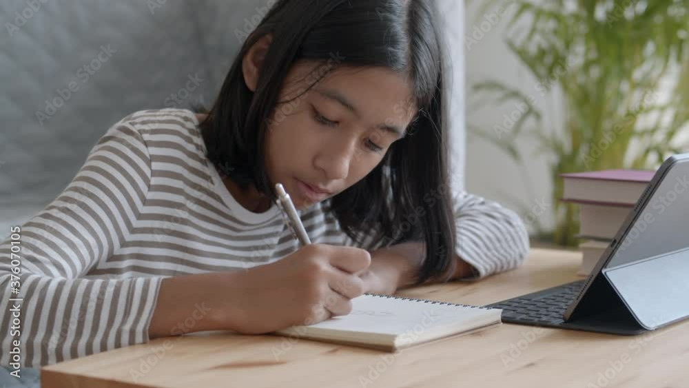 Asian girl is doing homework and using tablet at home morning Asian girl is doing homework and using tablet at home morning
