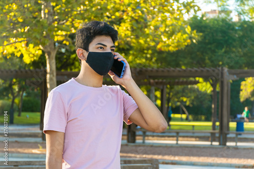 Young man talking on the phone with a medical mask