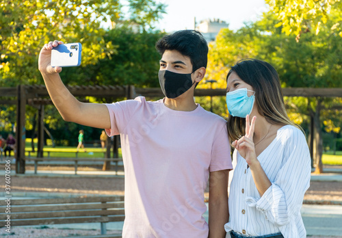 Girl and boy with face masks taking a selfie with a smartphone