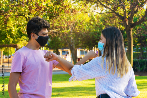 Girl and guy greeting with elbows outdoors