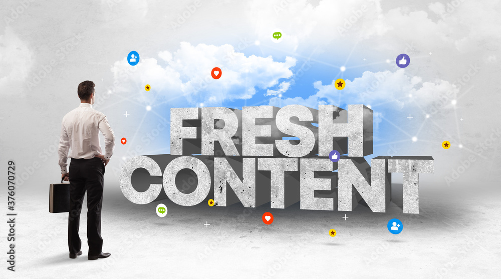 Young businessman standing in front of FRESH CONTENT inscription, social media concept Young businessman standing in front of FRESH CONTENT inscription, social media concept