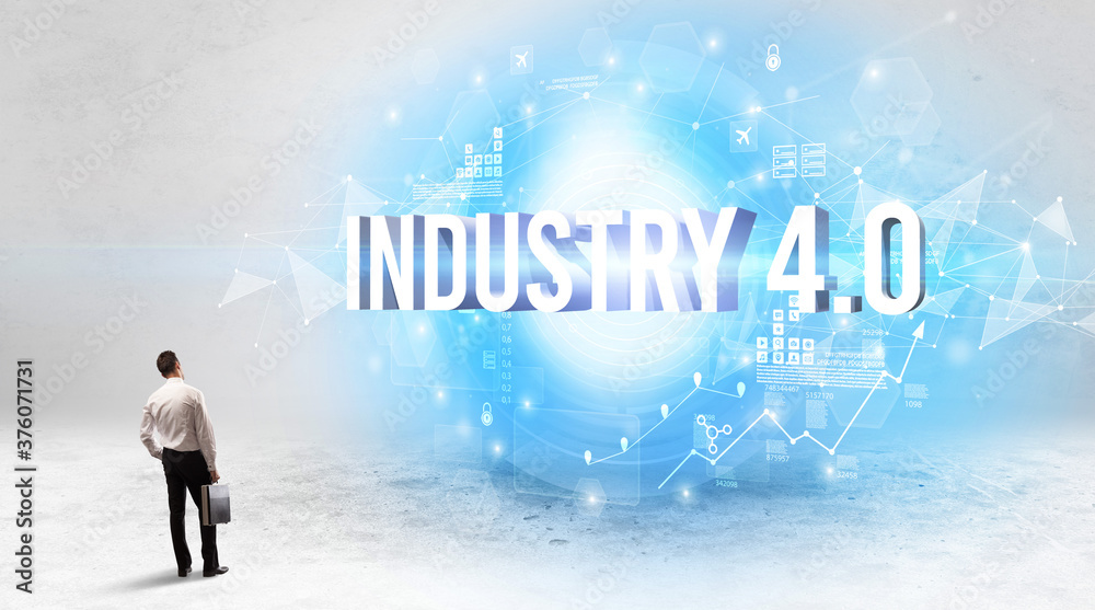 Rear view of a businessman standing in front of INDUSTRY 4.0 inscription, modern technology concept Rear view of a businessman standing in front of INDUSTRY 4.0 inscription, modern technology concept