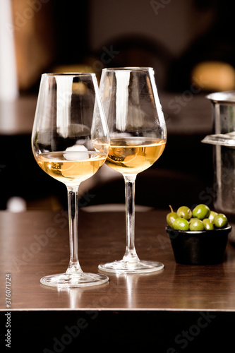 glasses with wine and olives, on the wooden table, inside the restaurant and free space for decoration.