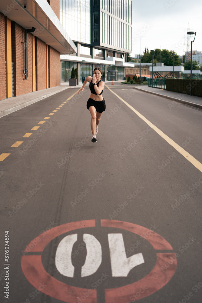 Young woman sprinting in the morning outdoors. Top view of female runner working out in the city. Young woman sprinting in the morning outdoors. Top view of female runner working out in the city.