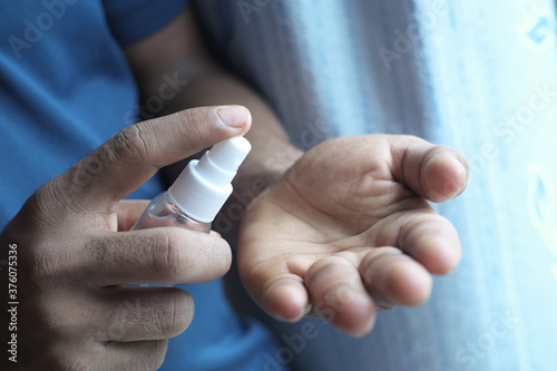 close up of young man hand using hand sanitizer spray.