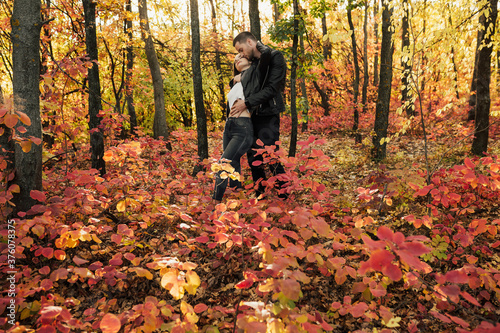 Passionate couple hugging and enjoying colorful, red and yellow autumn in the park. Concept of love, relationship, family, season and people