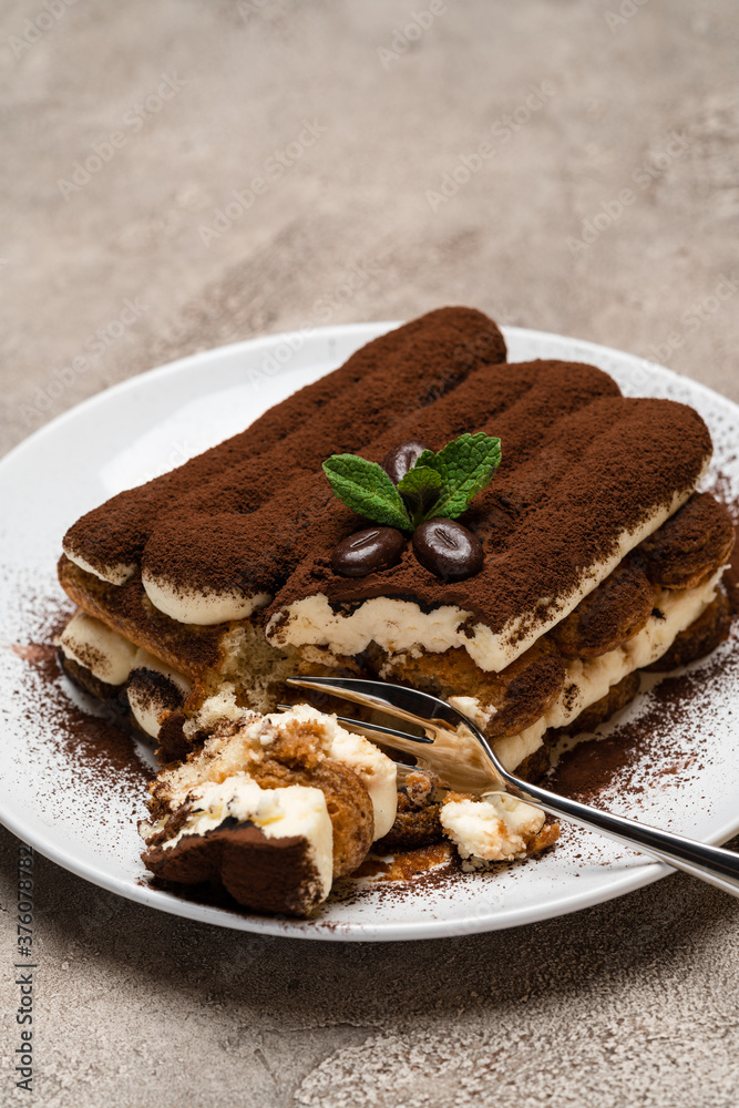 portion of Classic tiramisu dessert on ceramic plate on concrete background portion of Classic tiramisu dessert on ceramic plate on concrete background