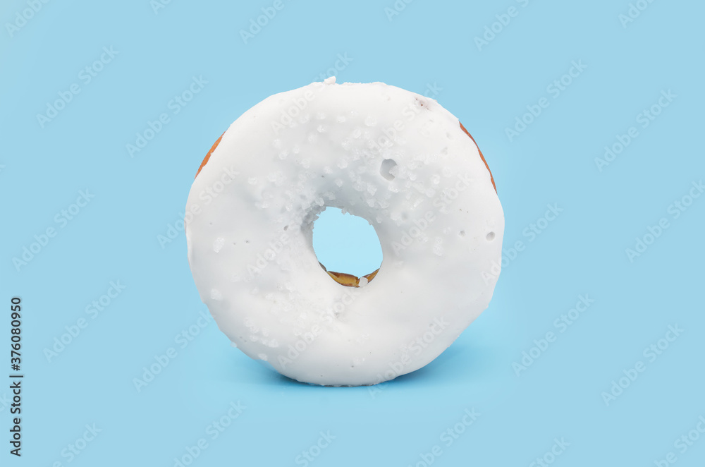donut with white chocolate icing isolated on blue background.