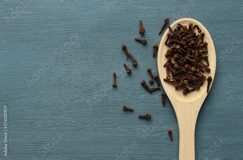 Spice clove scented in a wooden spoon on a dark background. Selective focus.