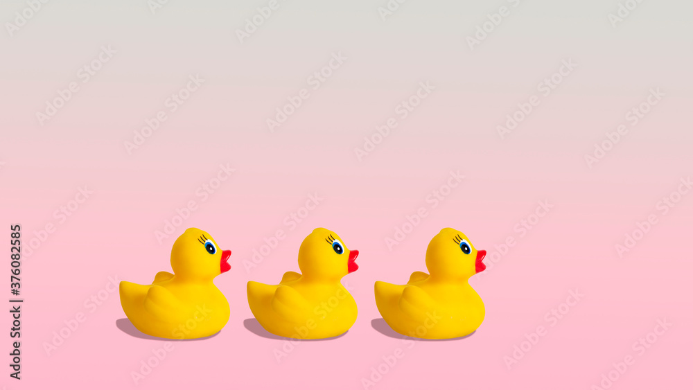 Yellow rubber ducks on a pastel pink background.