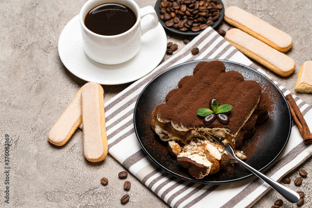 portion of Classic tiramisu dessert and savoiardi cookies on concrete background portion of Classic tiramisu dessert and savoiardi cookies on concrete background